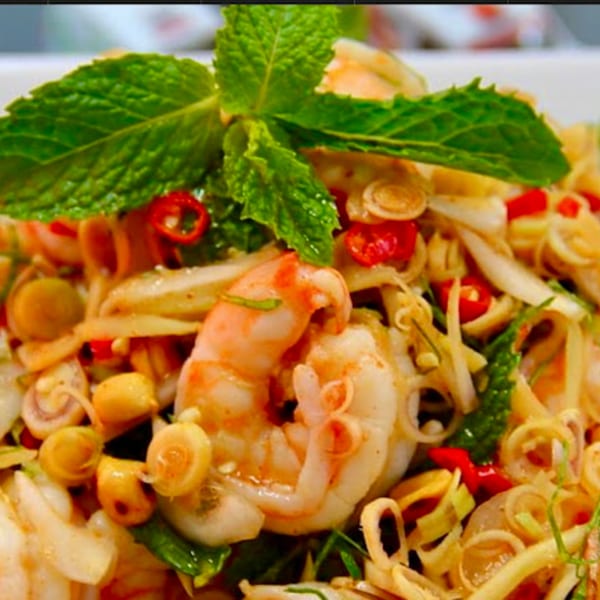 Close-up of a vibrant Thai salad with shrimp, mint, red chilies, and lemongrass.